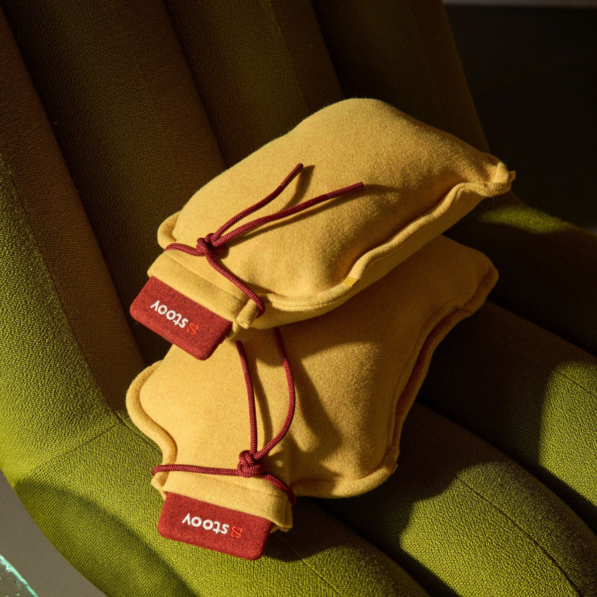 Stoov Homey Flex warmtekussen 25x35cm, geel, op een groene stoel, voor extra comfort en warmte indoor.